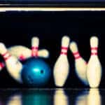 Blue bowling ball knocking over pins