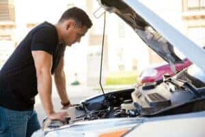 Man looking under hood of broken-down car