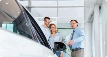Car salesman showing a couple a vehicle
