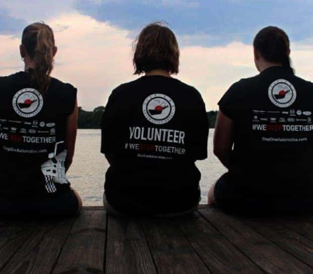 3 people sitting on a dock in step one uniforms facing away from camera