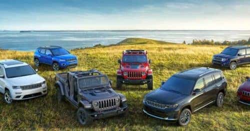 Group of CDJR vehicles on grass in front of water.