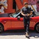man with camera standing beside red and black 2019 fiat 124 spider