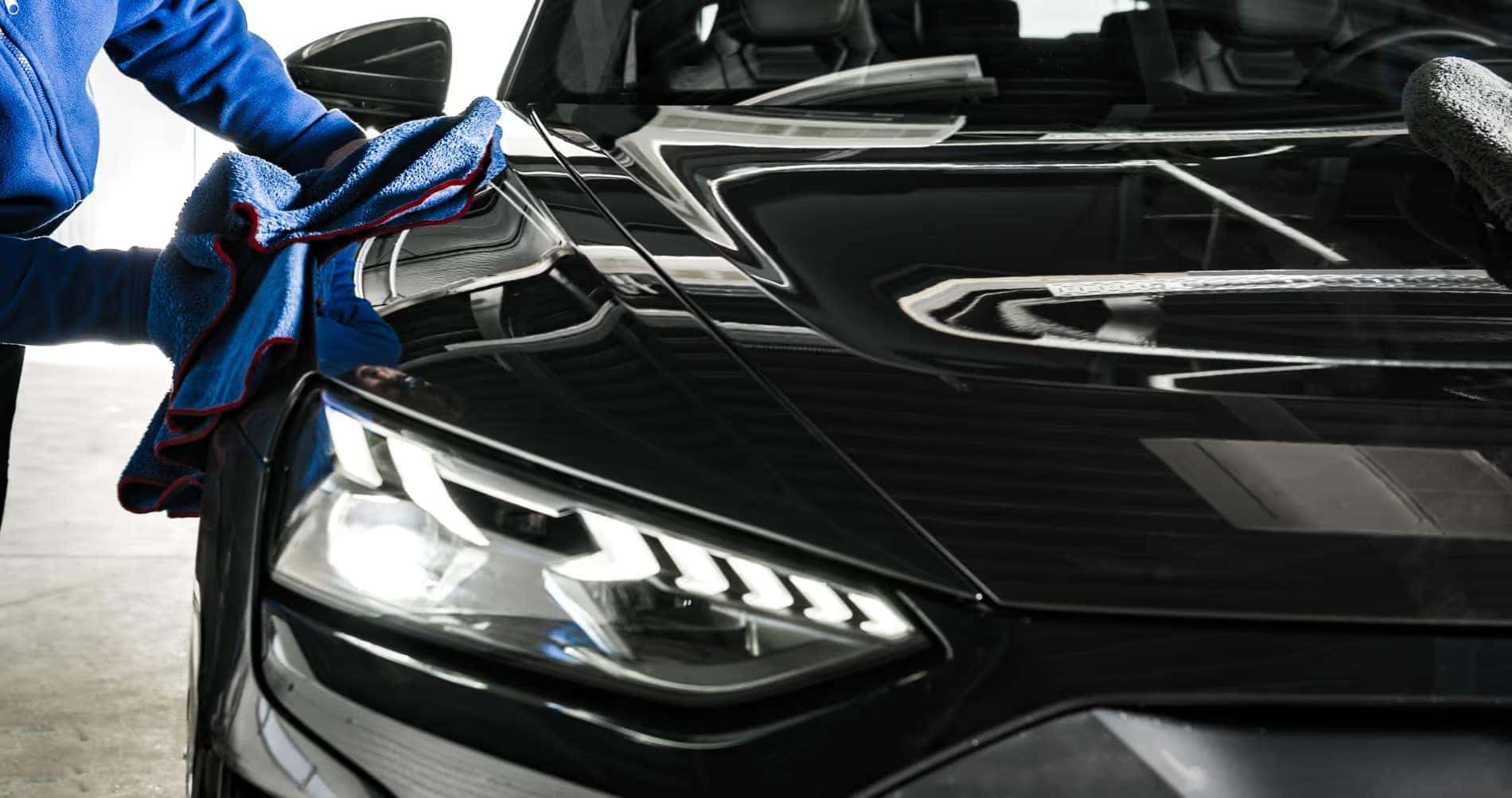 Person polishing a black car at Fisher Auto Spa