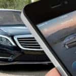 Person holding smartphone with Mercedes me app pulled up while facing a Mercedes-Benz vehicle