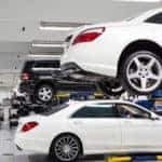 Service bay with white Mercedes-Benz on lift in foreground
