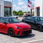 2026 Toyota Camry exterior design featuring red and black sport trims parked outside dealership showroom