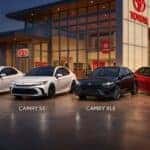 2026 Toyota Camry LE, SE, XLE, and XSE trim levels parked in front of a modern Toyota dealership showroom.