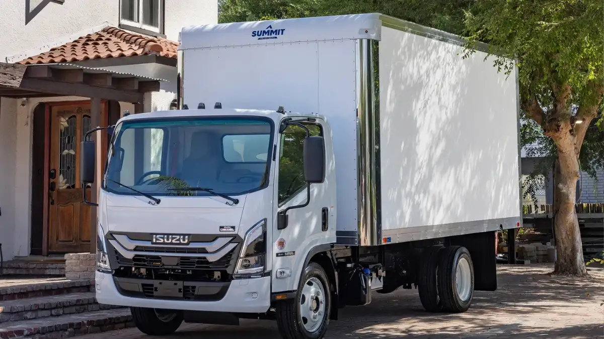 A white Isuzu N Series Diesel box truck parked in front of a nice house
