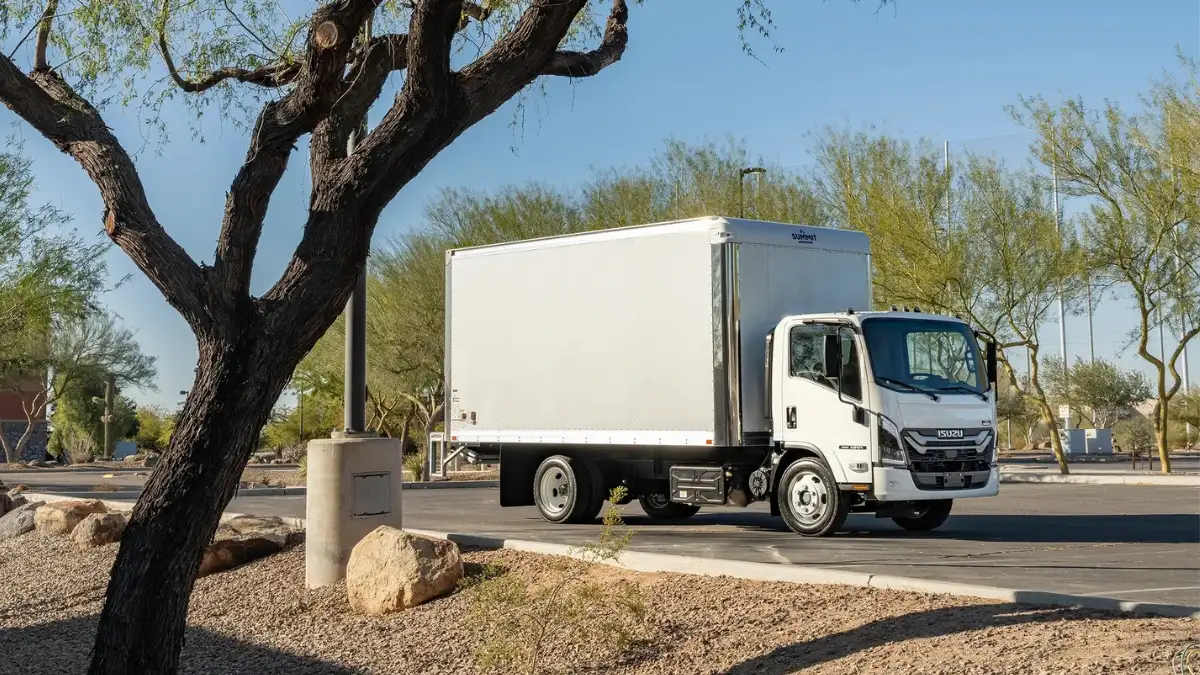 An Isuzu diesel truck driving through a parking lot at a park