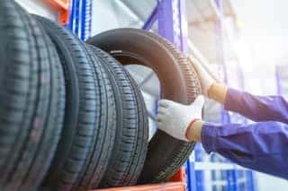 Technician wearing gloves picking tire from shelf