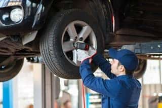 Technician installing tire to raised car in garage