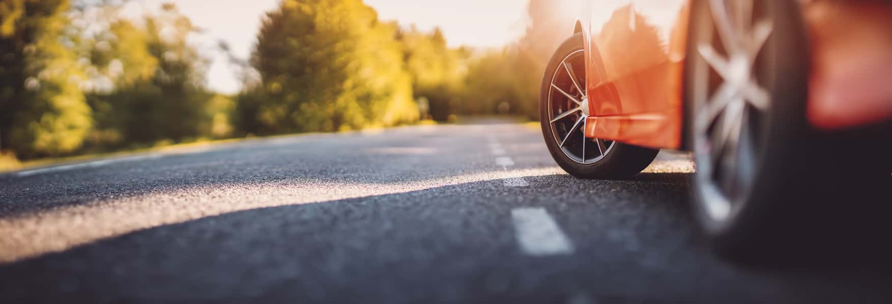 Red car on asphalt road in summer
