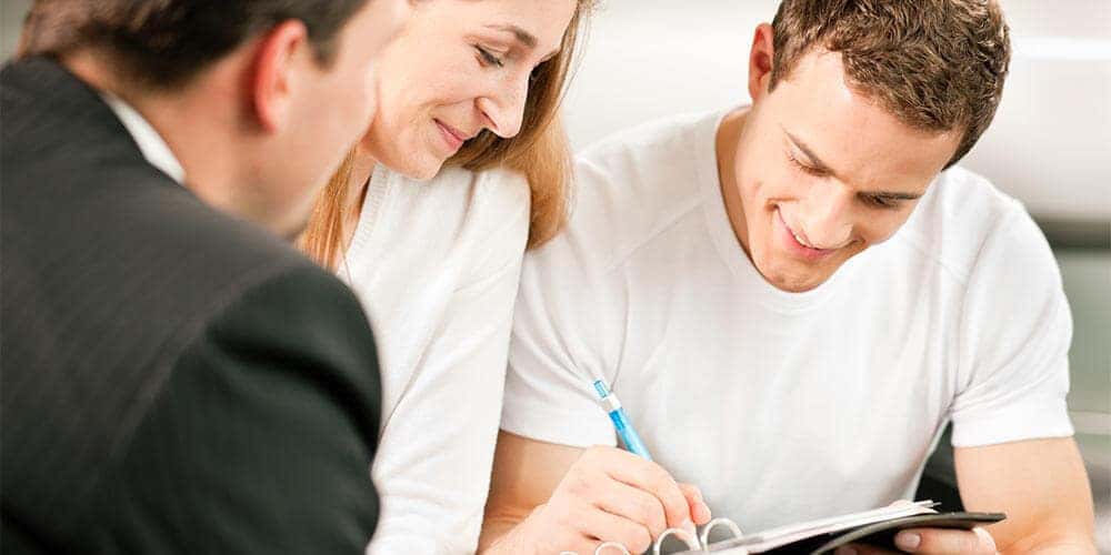 Couple signing paperwork for their new Mazda car