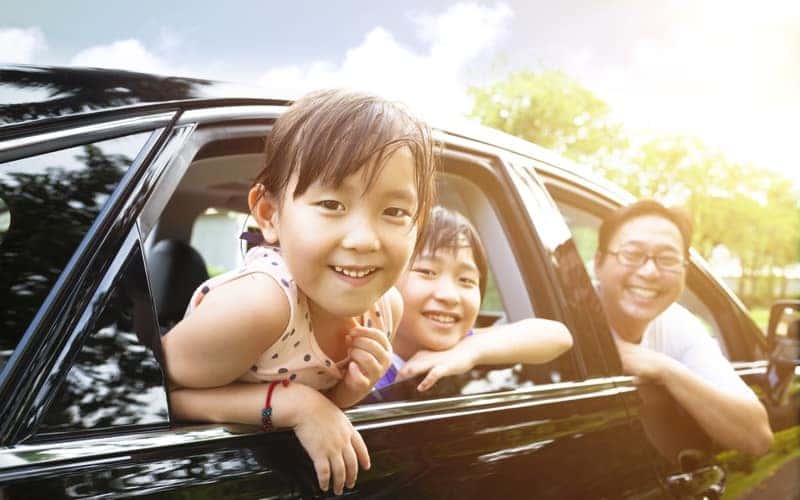 happy little girl with family sitting in the car