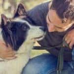 man kneeling with his dog on a walk