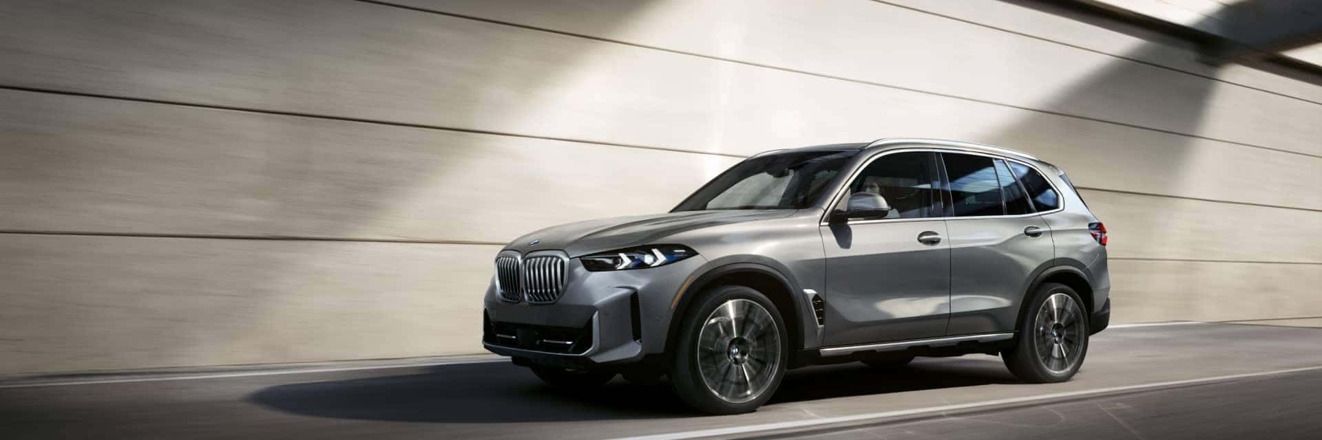 Silver BMW X5 driving on city highway