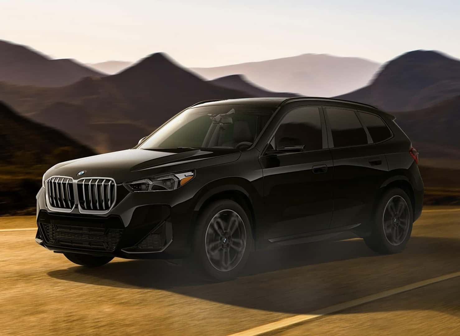 BMW X1 xDrive28i driving on road with mountain background