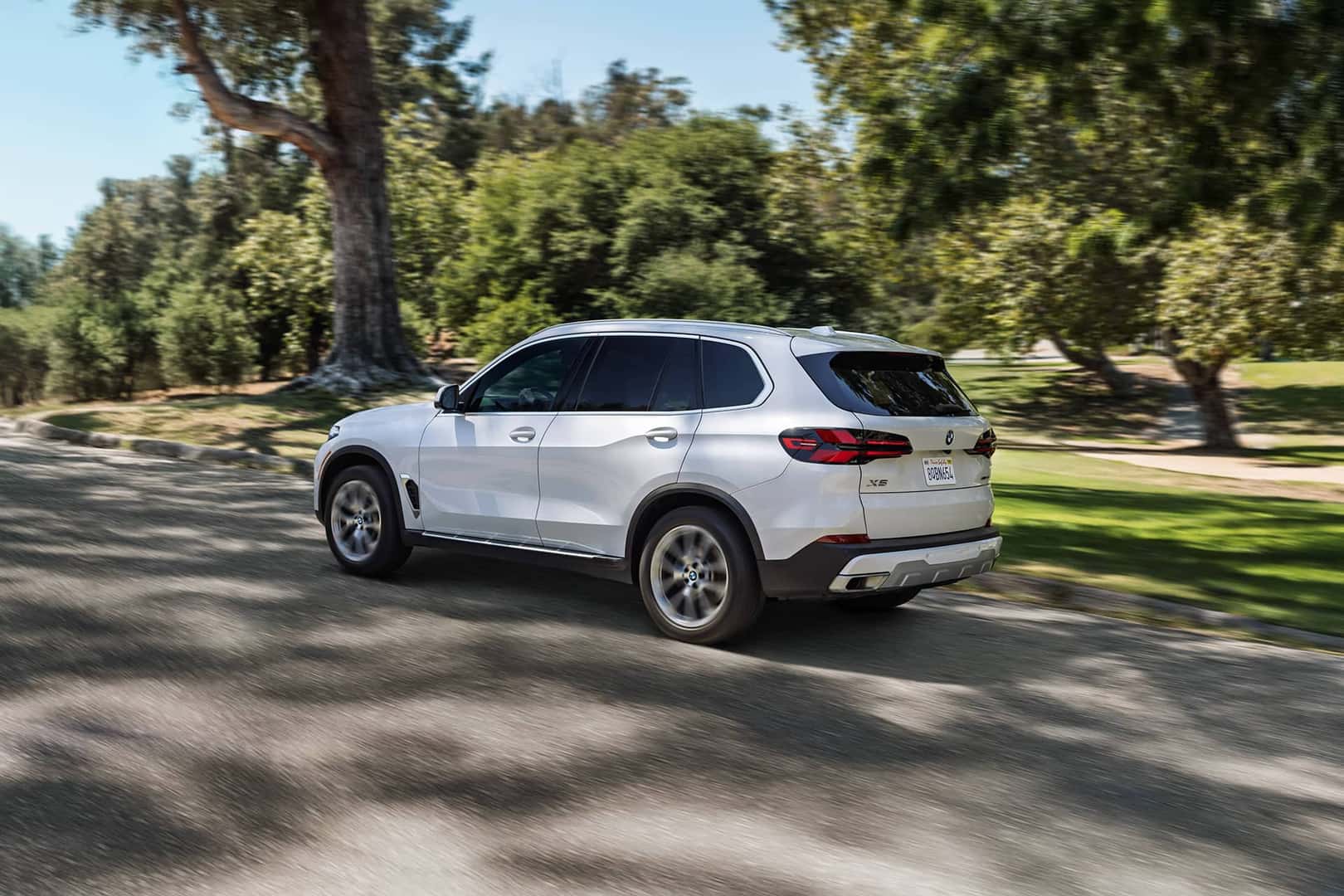 white bmw x5 driving on road