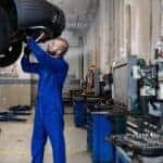 Vehicle on lift with mechanic servicing it