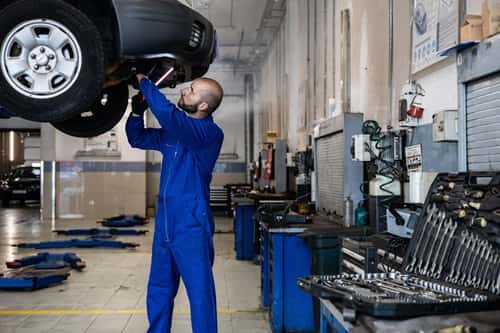 Vehicle on lift with mechanic servicing it