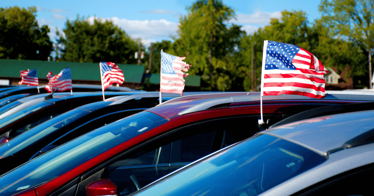 A row of parked cars with small, American flags on top of them