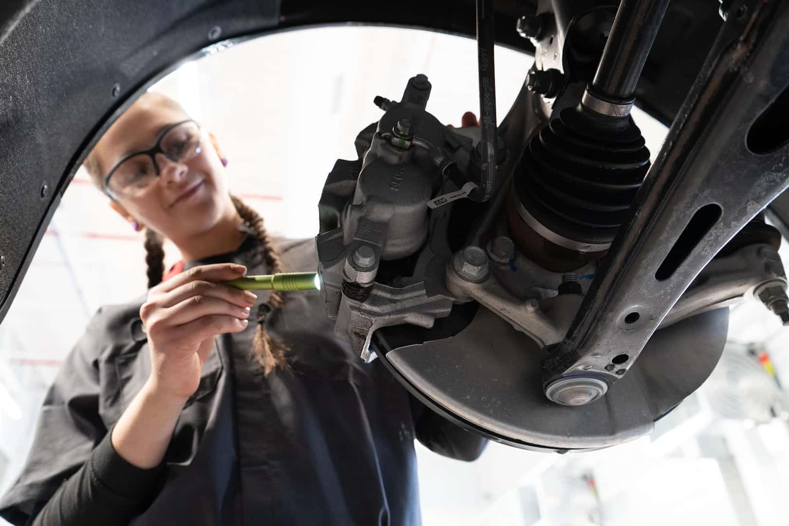 Cadillac Technician checking brakes with flashlight
