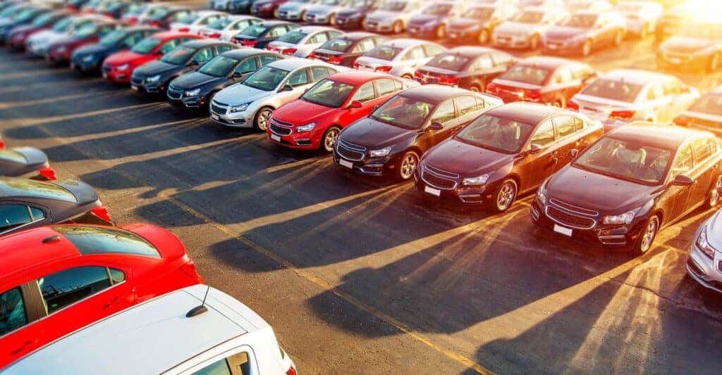 View of a used car lot with the sun reflecting off their windows.