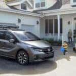 A family stepping out of the house towards their silver Honda Odyssey
