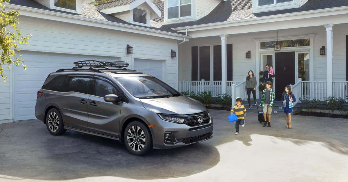 A family stepping out of the house towards their silver Honda Odyssey
