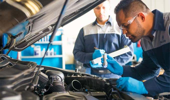 Two service technicians looking under the hood of an Acura in Nashua, NH