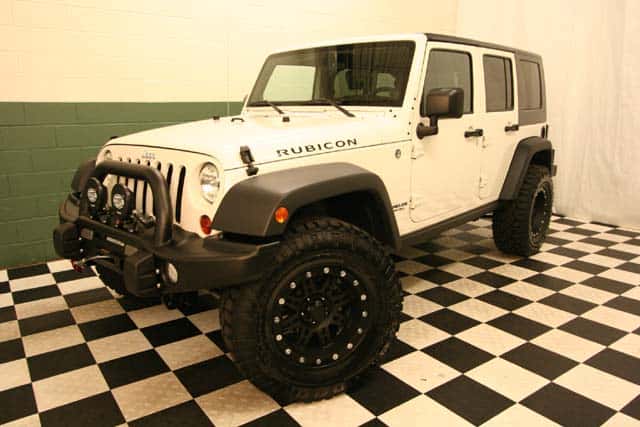 Front view of a customized White 4-door Jeep Wrangler Rubicon in a black-and-white checkered showroom