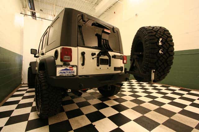 Back view of a customized White 4-door Jeep Wrangler Rubicon with the spare tire on a hinged carrier