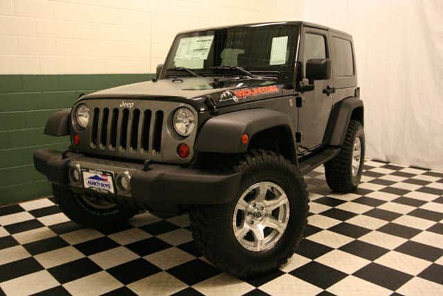 Front view of a customized Black Jeep Wrangler Mountain Edition in a black-and-white checkered showroom