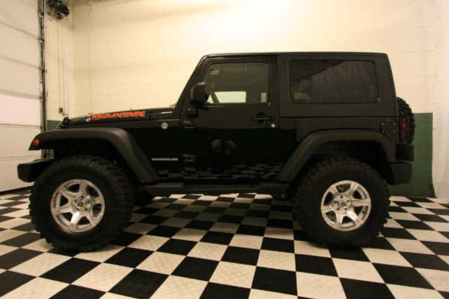 Front view of a customized Black Jeep Wrangler Mountain Edition in a black-and-white checkered showroom