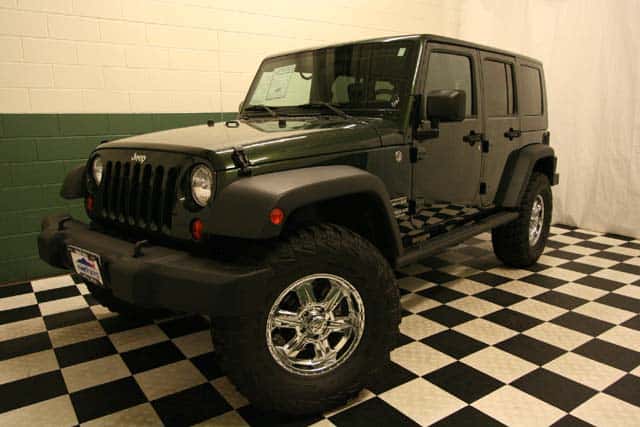 Front view of a customized Natural Green 4-door Jeep Wrangler in a black-and-white checkered showroom