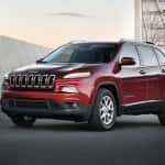 A red 2016 Jeep Cherokee parked in front of a modern building in Colorado Springs, CO.