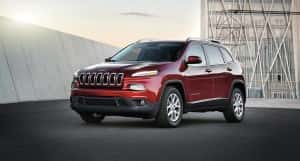 A red 2016 Jeep Cherokee parked in front of a modern building in Colorado Springs, CO.
