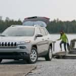 A couple in rain jackets heads to a silver Jeep Cherokee after a boat ride