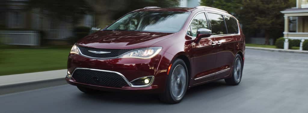 A dark red 2017 Chrysler Pacifica driving on a suburban street near Colorado Springs.