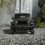 A green 2016 Jeep Wrangler Unlimited Willy's Wheeler is parked in front of a waterfall and shown from the front.