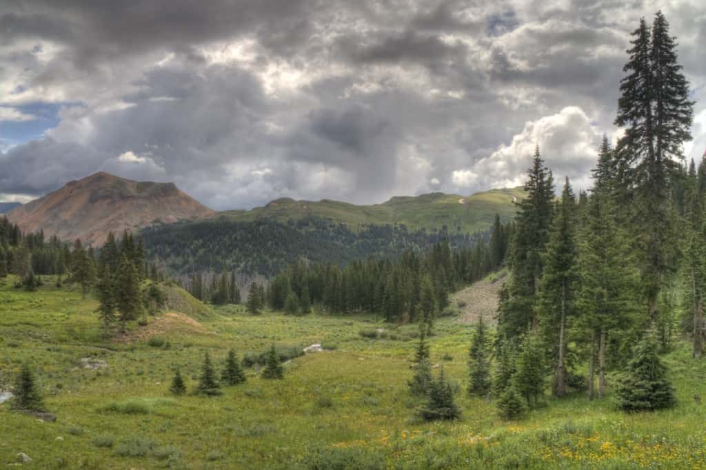 Black Bear Pass in Colorado: a mountainous landscape with green hills and a cloudy sky