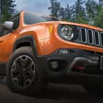 An orange 2015 Jeep Renegade is shown from a low angle on a woodland trail. Check one out today at your local Jeep dealership in Colorado.