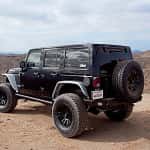 A black 2016 Jeep Wrangler Unlimited is parked atop a desert hill. Find an SUV like this at your Jeep dealers in Colorado.