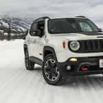 A white 2017 Jeep Renegade is driving on a snowy road.