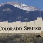 Stone Colorado Springs sign in front of tall mountains