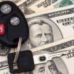 Black car keys on top of one-hundred and fifty-dollar bills