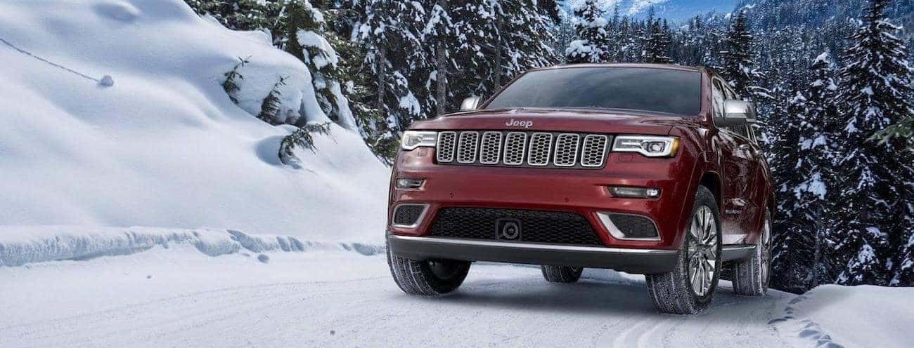 A red 2017 Jeep Grand Cherokee Overland driving in the snow