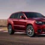 A red 2017 Jeep Grand Cherokee SRT from a Jeep dealership near Denver is driving around a racetrack.