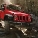A red 2017 Jeep Wrangler VLP Hero Rubicon offroading over large boulders in a misty forest