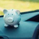 Blue piggybank sitting on the black dashboard of a vehicle